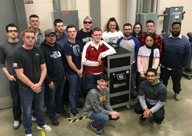 students at Pittsburg State University stand next to a 2 ton variable speed air cooler chiller that was donated by Delta T Systems